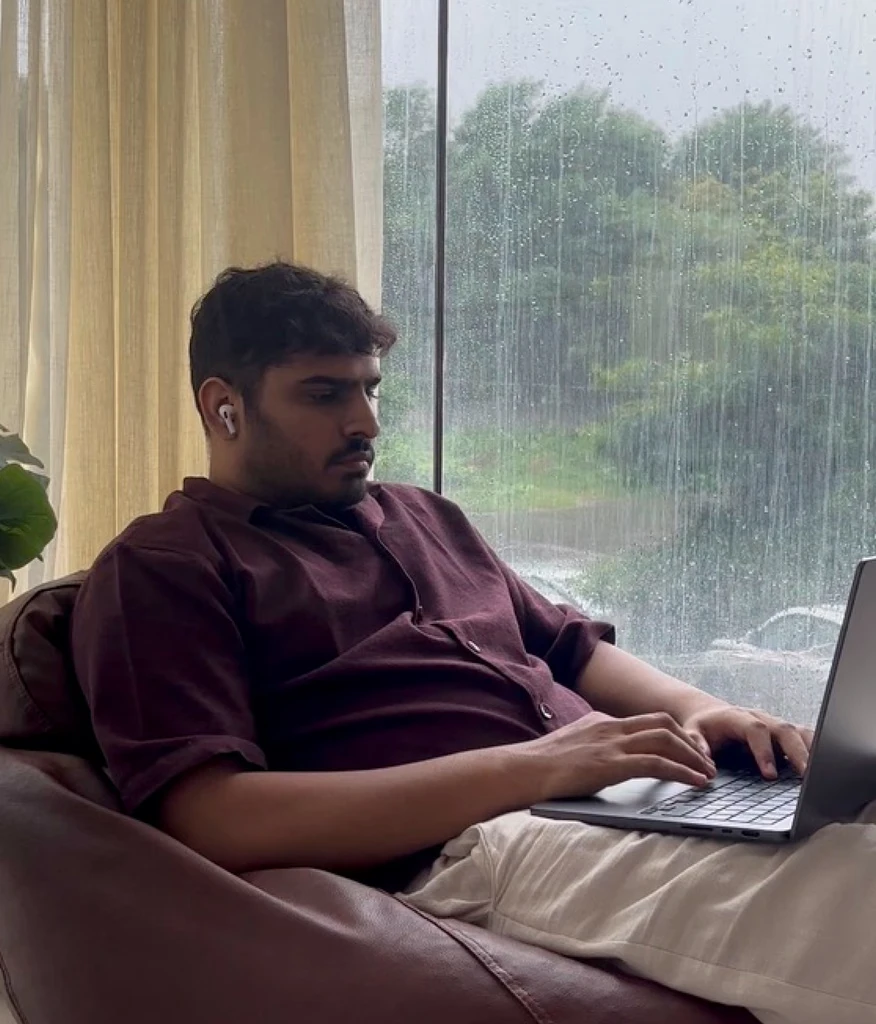 Rushil at work by a rain-streaked window